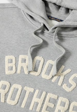 Grijze hoodie met crèmekleurige, gestructureerde borduursels die "BROOKS BROTHERS" spellen. De stof heeft een zachte, fleece-achtige textuur.