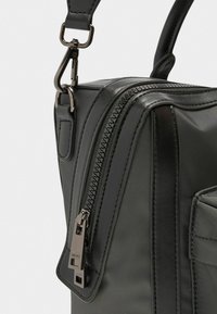 Schwarze Handtasche aus glattem Leder und Nylon, mit einem Reißverschluss und metallischen Hardwareakzenten. Kompakte Form mit abnehmbarem Trageriemen.