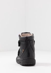 Stivaletto nero alla caviglia con esterno in pelle testurizzata, rivestimento in pelliccia nella parte superiore, chiusura a strappo in Velcro e suola in gomma.