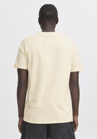 Lys gul bomull T-skjorte med rund hals og korte ermer, med et enkelt design og myk tekstur. Bakvisning som viser ensfarget stoff.