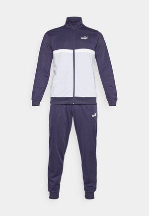 Tumed sinel tracksuit, millel on lukuga jakk, kus on valge triip. Valmistatud siledast materjalist, elastsete mansettide ja pükstega. Puma logo on välja toodud.