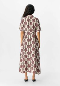 Robe maxi avec un motif floral dans des teintes de bordeaux et de vert sur un fond clair. Manches courtes et col. 