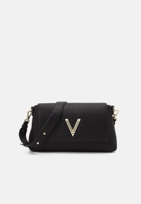 Sac à main en cuir noir au design structuré, avec une accentuation en forme de V doré et une bandoulière amovible. Fini texturé.