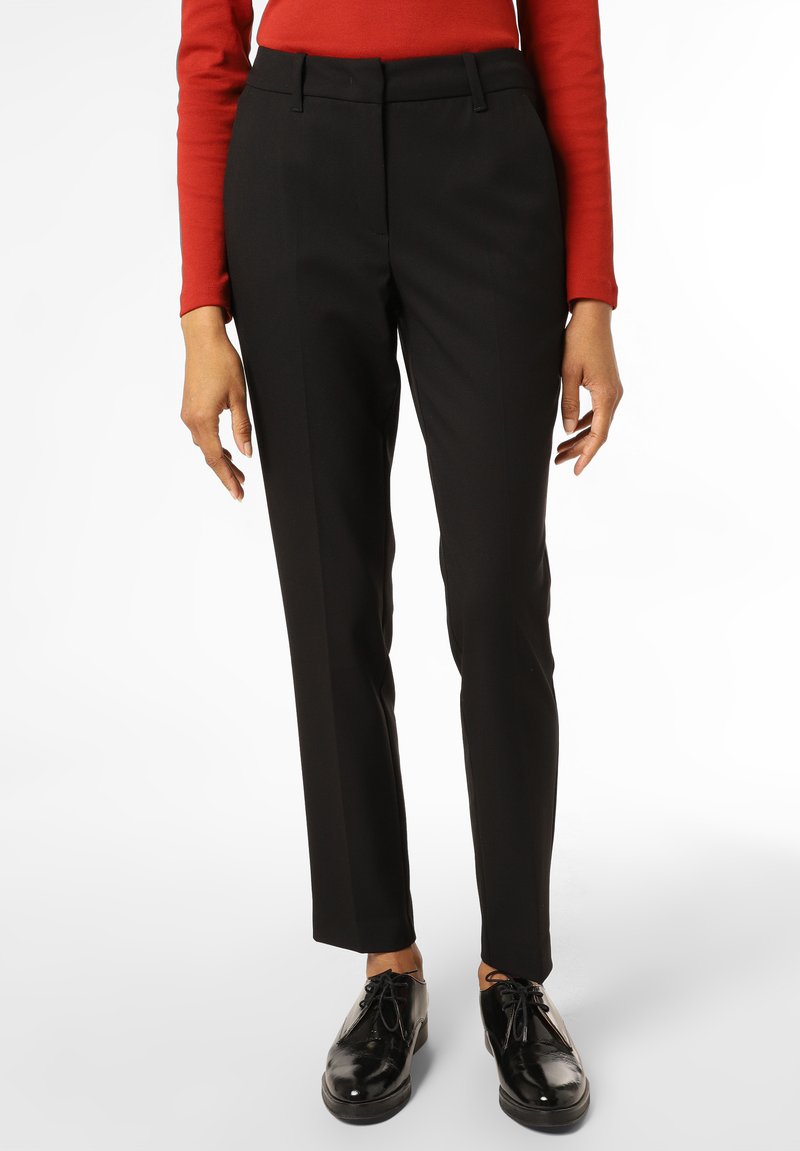 Pantalon noir cintré avec une coupe slim, doté d'un devant plat, de passants de ceinture et de poches latérales, associé à des chaussures à lacets noires brillantes.