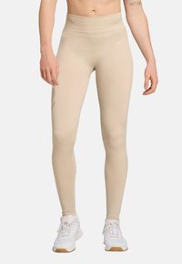 Beige high-waisted leggings gemaakt van rekbare stof, met een naadloos ontwerp en geribbelde textuur langs de benen.