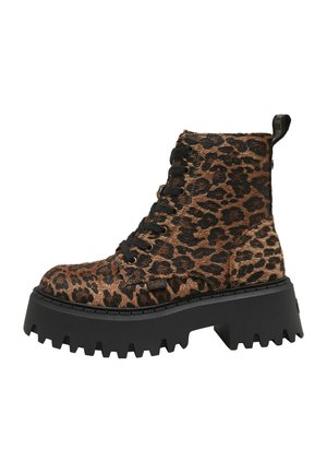 Bottine à plateforme épaisse avec imprimé léopard noir et marron, lacets noirs et semelle épaisse à crampons sur fond blanc.