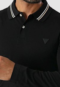 Czarna koszulka polo z długim rękawem i paskowanym kołnierzem, z zapięciem na guziki oraz małym trójkątnym logo na piersi.