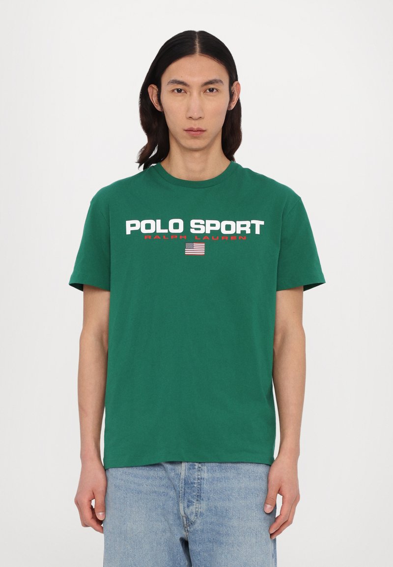 Camiseta de algodón verde con mangas cortas que presenta "POLO SPORT" y "RALPH LAUREN" en texto blanco y rojo, y un pequeño emblema de bandera.