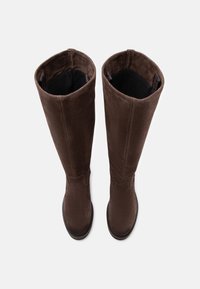 Botas de ante marrón hasta la rodilla con una textura suave, puntera redondeada y un sutil detalle de costura en el eje. El forro interior es negro.