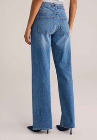 Visoke jeans iz modrega denima s sproščenim krojem. Oljna tekstura, oblikovanje s petimi žepi in subtilne šive na pasu.