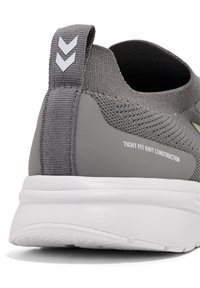 Grijze gebreide sportschoen met een strakke pasvorm, een gestructureerd oppervlak en een witte zool met minimalistische details.