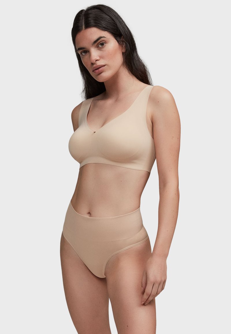 Bralette nu sans couture avec de larges bretelles, des bonnets doux et un col en V subtil. Culotte taille haute assortie avec une texture lisse et une coupe simple.