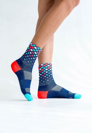 Bunt gemusterte Socken mit einem navyfarbenen Grund, darauf sind rote, blaue und weiße Rautenmuster zu sehen, die durch einfarbige rote und blaue Abschnitte an den Zehen akzentuiert werden.