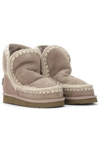 Botas de ante beige con un forro suave y mullido. Presentan costuras trenzadas de color claro a lo largo del cuello y suela de goma para mayor tracción.