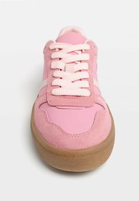 Baskets roses avec une tige lisse, des accents en daim et une semelle en caoutchouc texturée. Conçues avec des lacets épais et des rayures blanches contrastantes.