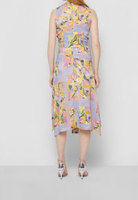 Robe sans manches avec un design patchwork présentant des motifs floraux vibrants en jaune, rose et vert sur un fond bleu clair.