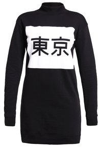 Mustapaita, jossa on korkea kaulus, ja jossa on valkoinen alue mustilla japanilaisilla merkeillä. Pehmeä materiaali, rento leikkaus ja pitkät hihat.