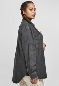 Overdimensjonert mørk denimskjorte med knapp-åpning krage, enkelt frontlomme, og lange ermer, med buet søm og myk tekstur.