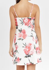 Blommig klänning med spagettiband, vit bakgrund, rosa rosor, gröna blad, figursydd byst, utsvängd kjol, slätt tyg, knälång.