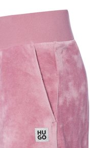 Roze velours joggingsbroek met een elastische tailleband, zijzakken en een klein zilveren "HUGO" logo label aan de voorkant. Zachte textuur met een subtiel patroon.