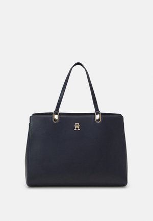 Navy leather tote bag with gold-tone hardware, two shoulder straps, and a prominent embossed logo on the front. Smooth texture, structured shape.