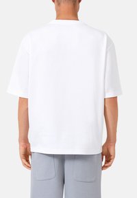 Witte katoenen t-shirt met een relaxte pasvorm, korte mouwen en een ronde hals. De achterkant toont een gladde, egale stof zonder patronen.