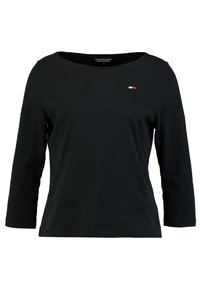 Schwarzes Langarmshirt mit weitem Ausschnitt und kleinem gesticktem Logo in Rot, Weiß und Blau auf der linken Brust. Weiches Baumwollmaterial.