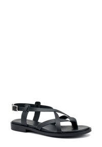 Sandalo in pelle nera con più cinturini incrociati, design open-toe e fibbia regolabile alla caviglia. Sole piatto dallo stile minimalista.