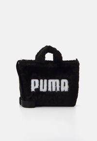 Sort faux fur taske med en fast form, der har et fremtrædende hvidt "PUMA" logo, korte hanke og en justerbar skulderrem.