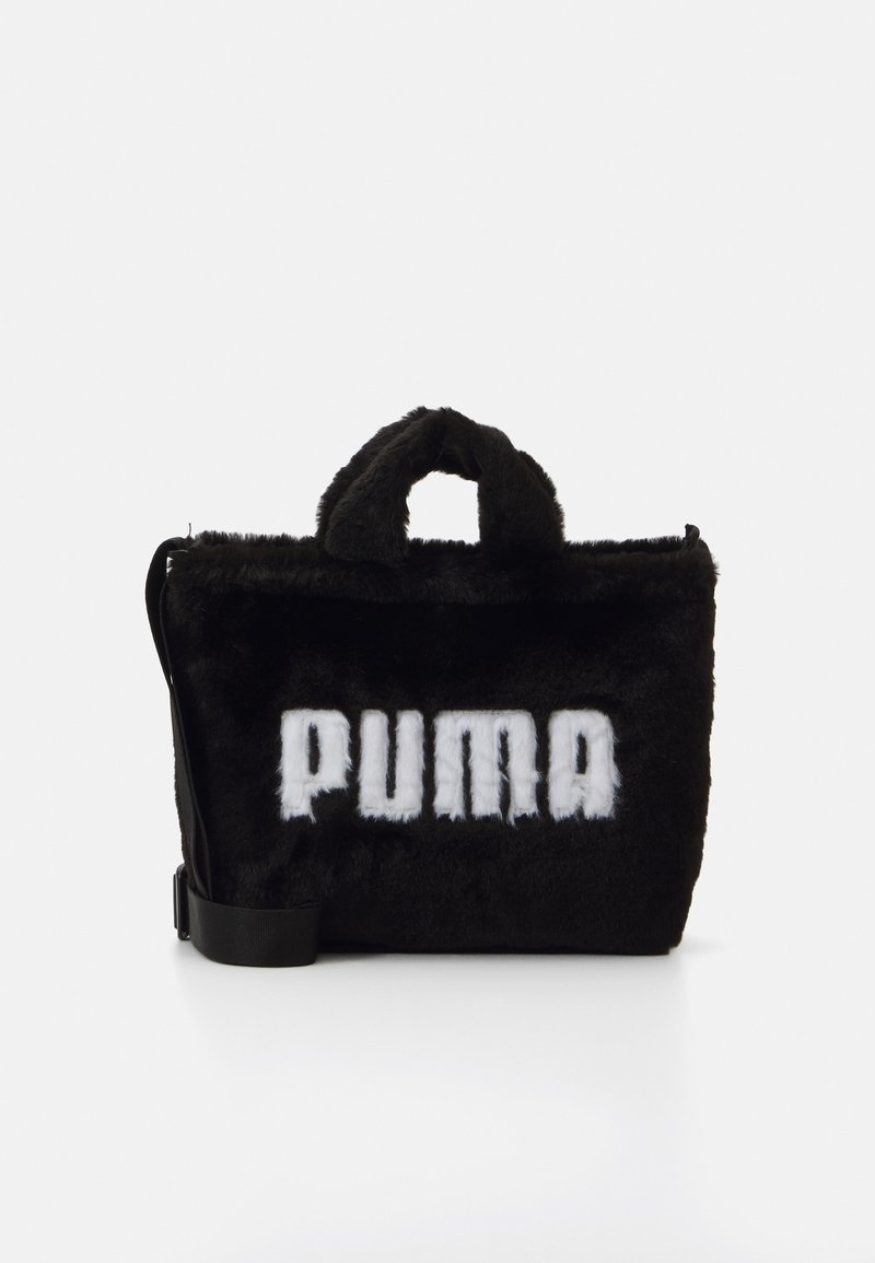 Sort faux fur taske med en fast form, der har et fremtrædende hvidt "PUMA" logo, korte hanke og en justerbar skulderrem.