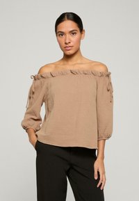 Top bez ramínek, světle hnědé, vyrobený z texturovan�é látky. Má volánkový výstřih, zavazování na ramínkách a rukávy do tří čtvrtin.