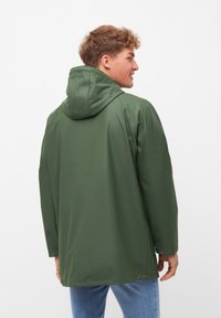 Giacca impermeabile verde con cappuccio, caratterizzata da una texture liscia, design dritto, maniche lunghe e chiusure a scatto ai polsini.