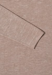 Hellbrauner Strickstoff mit feiner Textur, der einen diagonalen Ärmelschnitt aufweist. Das Material sieht weich und leicht aus.