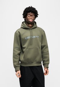 Olivgrüner Hoodie aus Baumwollmischung, mit einer Fronttasche, Kapuze mit Kordelzug und besticktem "Carhartt"-Logo in Hellblau.