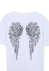 T-shirt bianco in cotone con una grafica di ali piumate nere stilizzate stampata sulla schiena, caratterizzata da dettagliati lavori di linea e ombreggiatura.