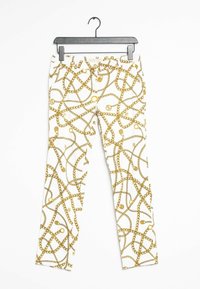 Pantalones blancos con un patrón de cadena dorada, que presenta enlaces intrincados y acentos redondos. El material parece suave y liviano.