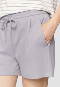 Světle fialové sportovní šortky s elastickým pasem a šňůrkou, s bočními kapsami a hladkou texturou.