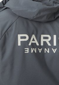 Veste gris foncé avec une capuche affichant un texte blanc lisant "PARIS" et des lettres à l'envers "ENAME" dans le dos.