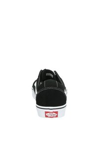 Zapatilla negra con parte superior de ante y tejido, costuras blancas, suela de goma y logotipo rojo en el talón. Diseño de perfil bajo con puntera redondeada.