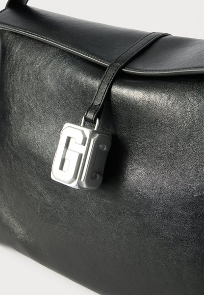 Borsa in pelle nera con una texture liscia, dotata di un pattina ripiegata e di una chiusura con logo in argento. Il design è minimalista con linee pulite.