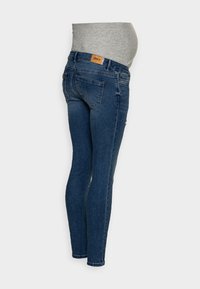 Jeans de maternidad de denim en un lavado azul oscuro con una cintura alta y elástica. Presenta dos bolsillos traseros y un diseño de pierna ajustada.