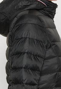 Czarna kurtka puchowa z pikowaną fakturą, z kapturem i gładką, błyszcząca nawierzchnią. Widoczny zamek błyskawiczny oraz kolorowe akcenty na kołnierzu.