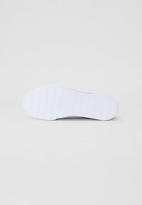 Bílá podrážka boty s horizontálními drážkami, hladkým gumovým povrchem a bez viditelného loga či vzorů. Jednoduchý a funkční design.