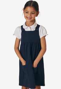 Granatowa bawełniana sukienka z marszczoną spódnicą, guzikami na ramionach i bocznymi kieszeniami. Biała koszula z kołnierzykiem pod spodem. Gładka tekstura i casualowy design.