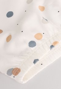 Tela de algodón con fondo blanco con lunares multicolores en azul claro, melocotón, gris y negro. Detalle de dobladillo elástico.