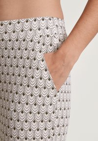 Witte gestreepte broek met een golvend patroon in donkergroen. De stof heeft een gladde textuur en bevat een zijzak.