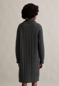 Donkergrijs, geribbelde gebreide jurk met lange mouwen en hoge hals. Heeft een gestructureerde stof en een middellange snit die boven de knieën eindigt.