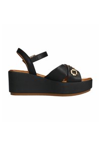 Zwarte wedge sandalen hebben brede leren banden, een verstelbare enkelband en een zwarte platformzool met textuur en een gouden accent detail.