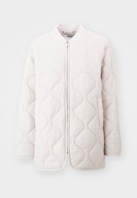 Veste matelassée beige clair avec fermeture éclair, col côtelé et motif de couture ondulé. Dispose de deux poches latérales.