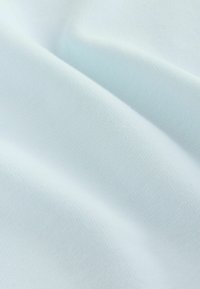 Tissu en coton bleu clair avec une texture lisse et mate, présentant des nervures subtiles et un tombé doux, idéal pour la confection de vêtements.